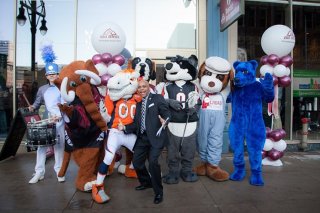 Denver Mayor Michael B. Hancock poses with associated with town's mascots before VISIT DENVER's recently established advanced Tourist Information Center.